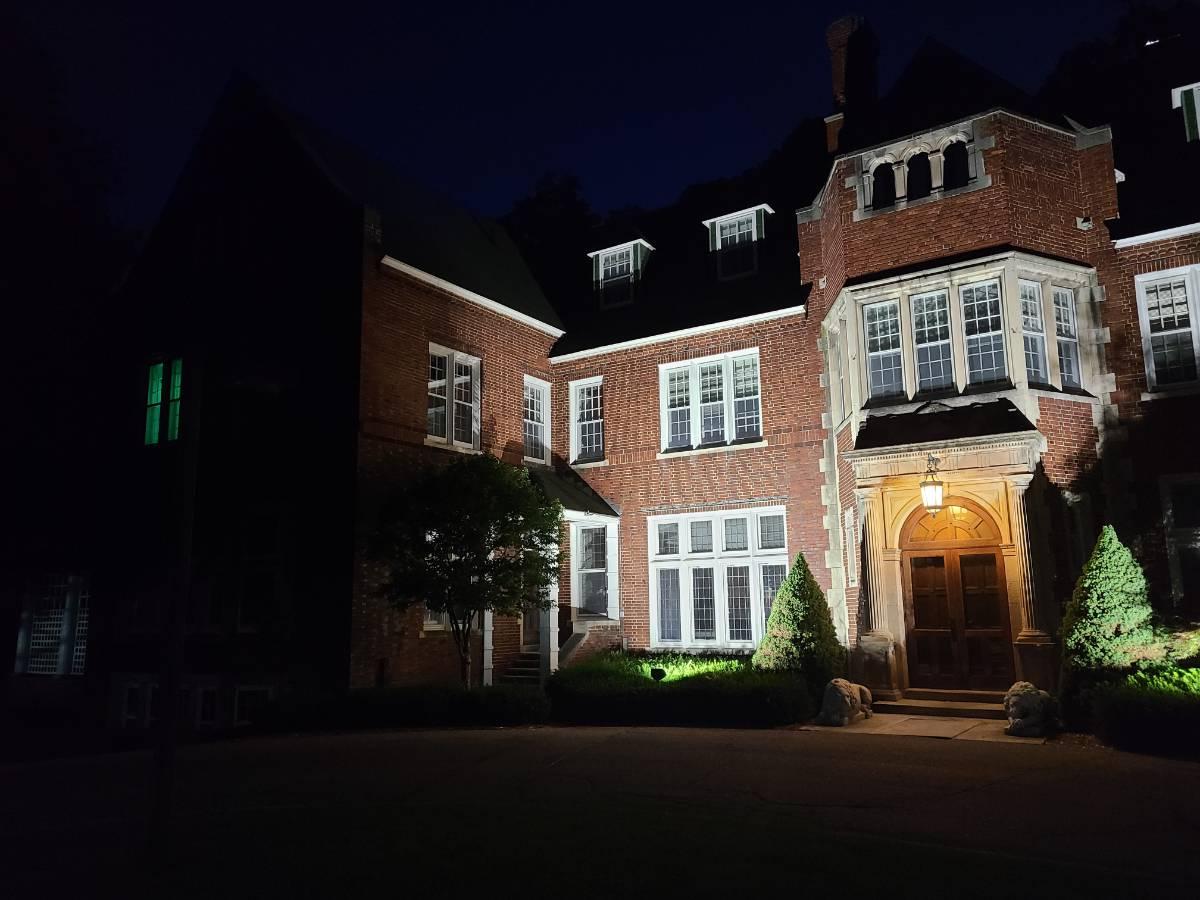 夜晚福尔摩斯庄园的正面，有上光，窗户上有一盏闪闪发光的绿光